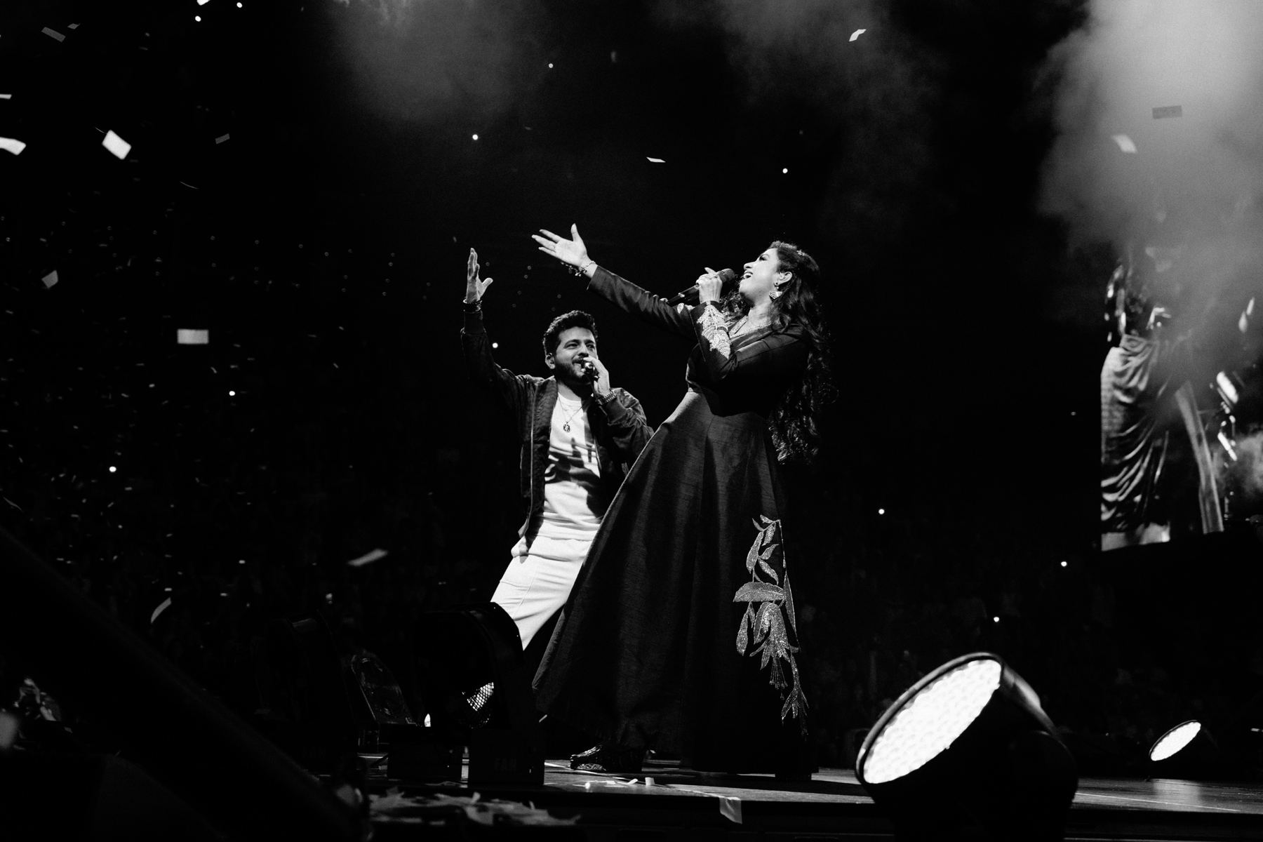 Duet with arms raised in a haze of confetti