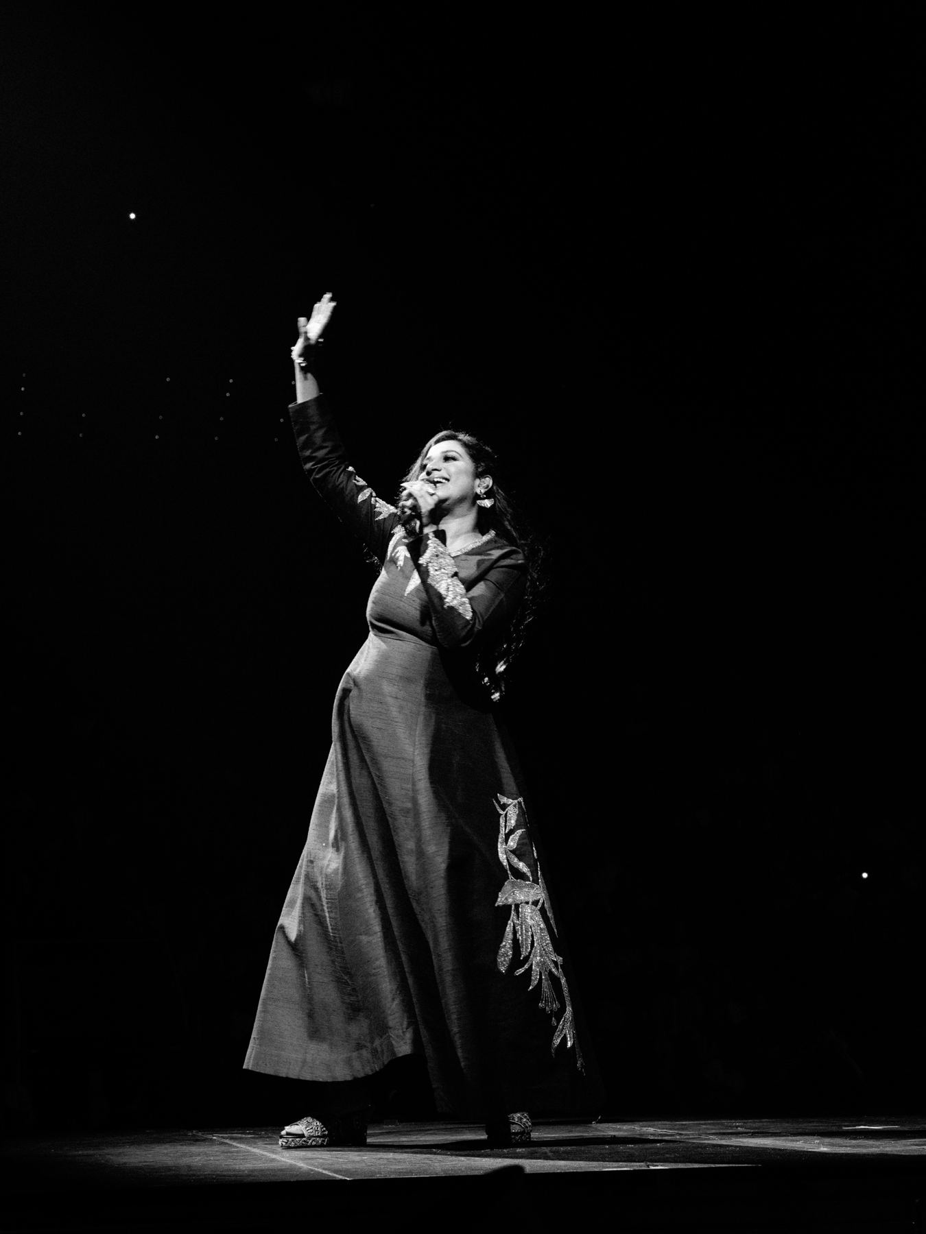Singer waving to the crowd under a single spotlight